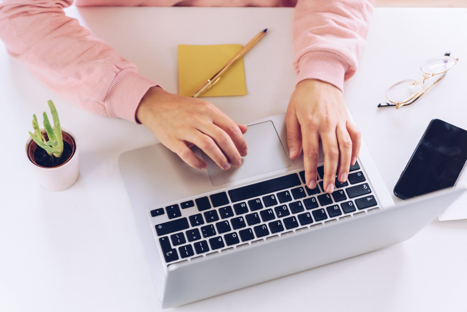 Woman Typing on Laptop on White Desk